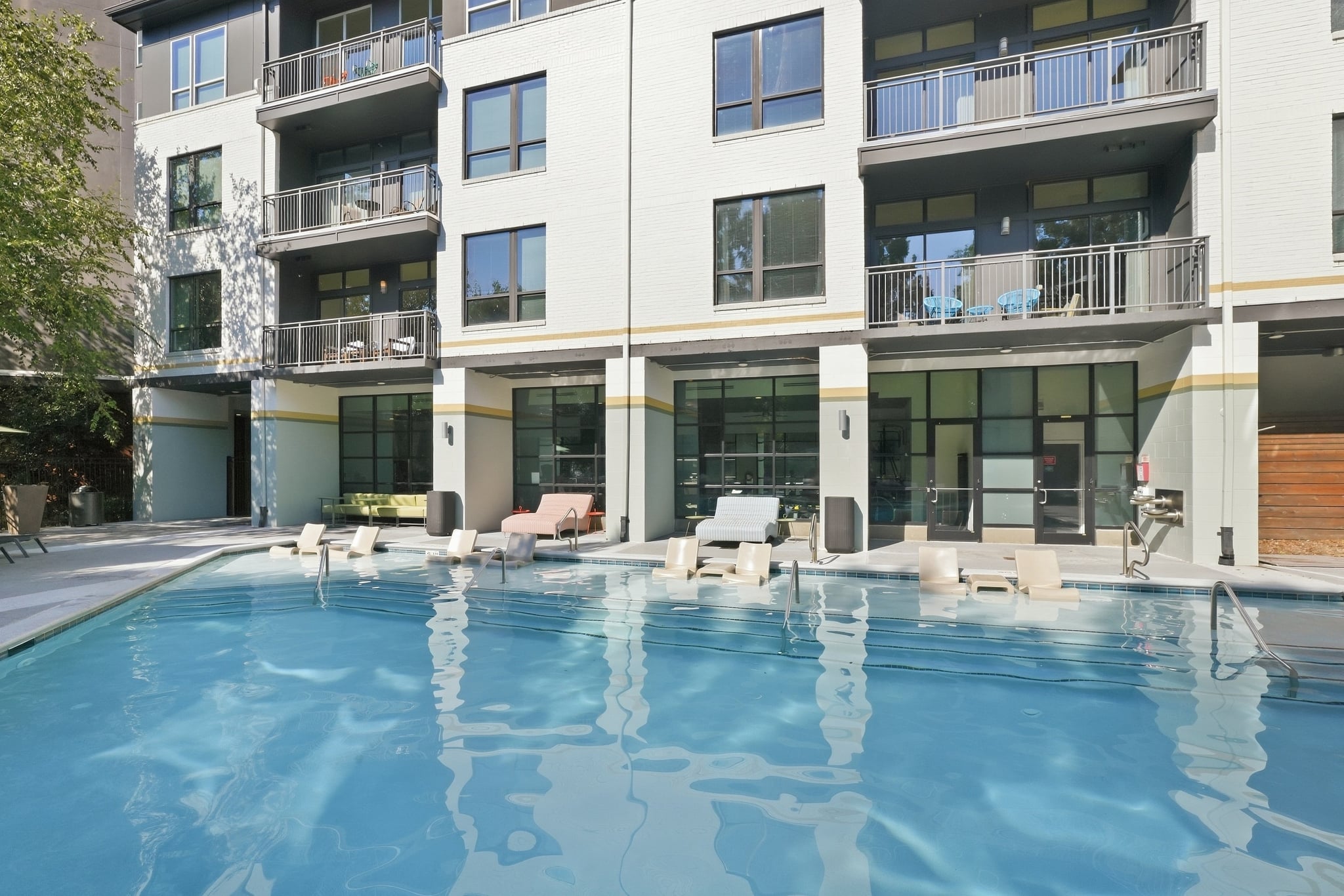 A large swimming pool in front of a modern apartment building.