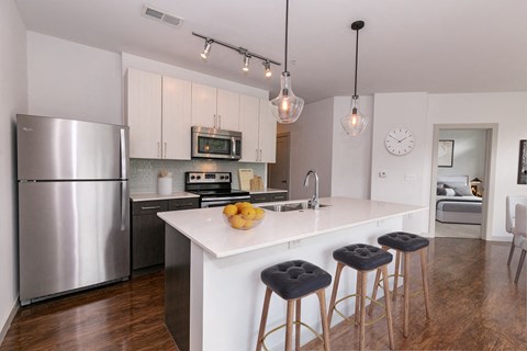 a kitchen with stainless steel appliances and a large island with three stools