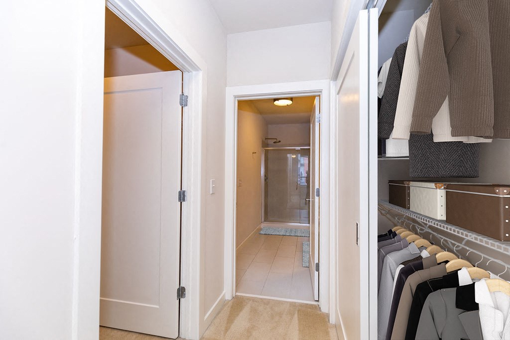 a closet with a mirrored door and a hallway to a bathroom