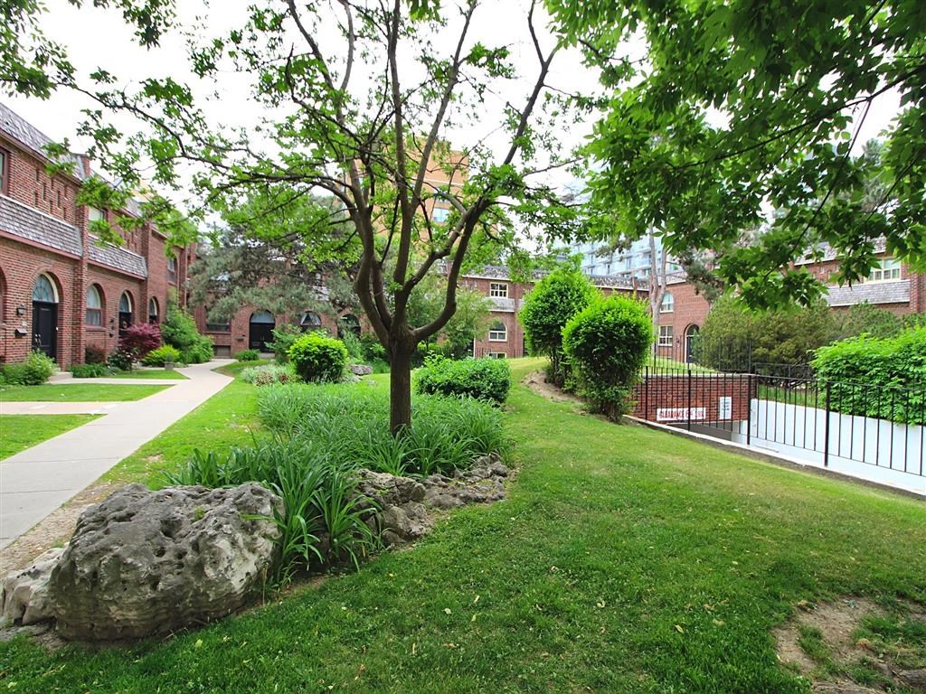 a yard with a rock and grass and trees and buildings
