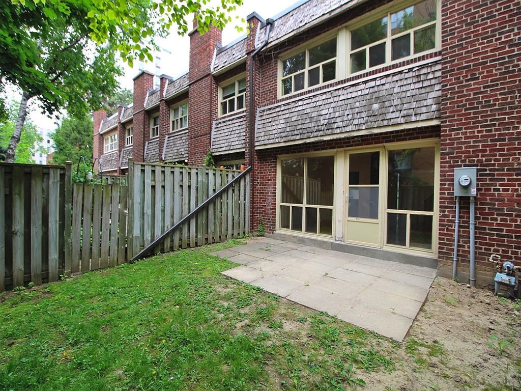 the back of a brick house with a patio and a wooden fence
