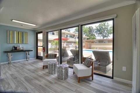 a living room with chairs and a view of a pool