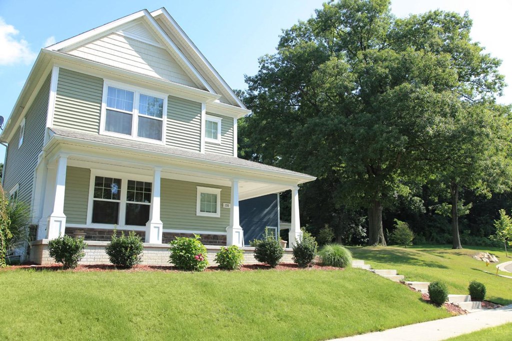 a green house with a lawn and trees