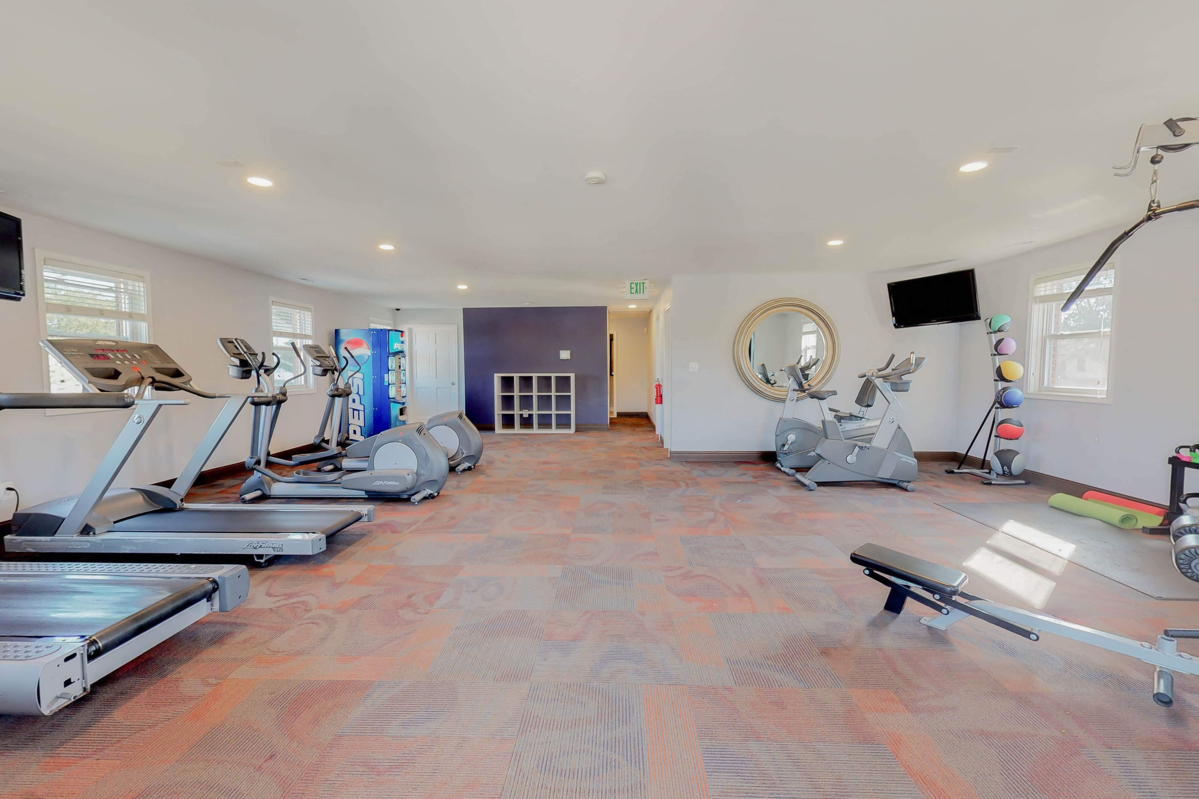 a gym with treadmills and other exercise equipment in a room with a window