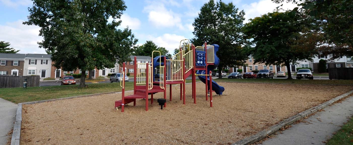 a playground with a slide and chairs in a park