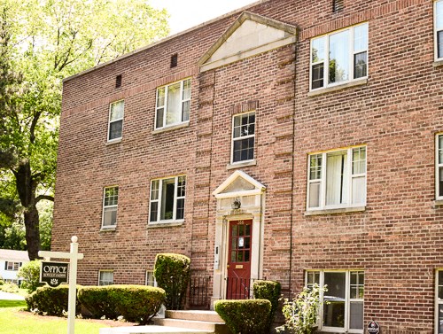a brick building with a red door and a sign in front