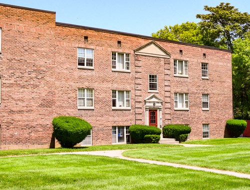 a red brick building with a green lawn in front of it