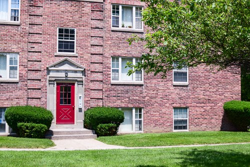 the front of a brick house with a red door