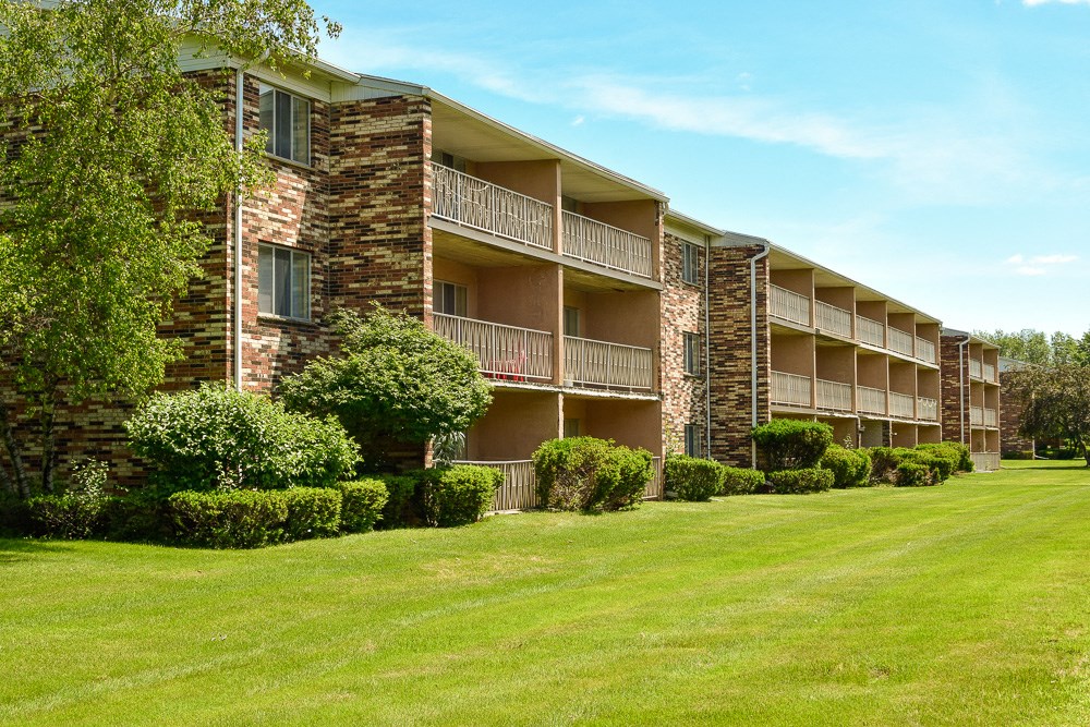 an exterior view of an apartment building with a green lawn