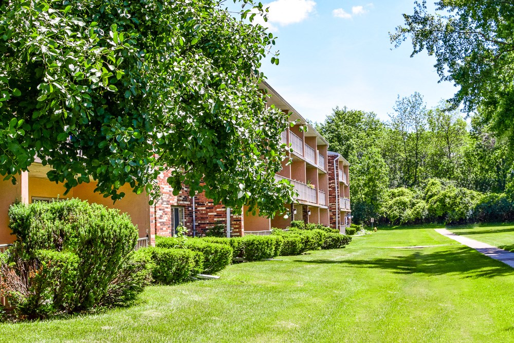 a green yard in front of a brick apartment building