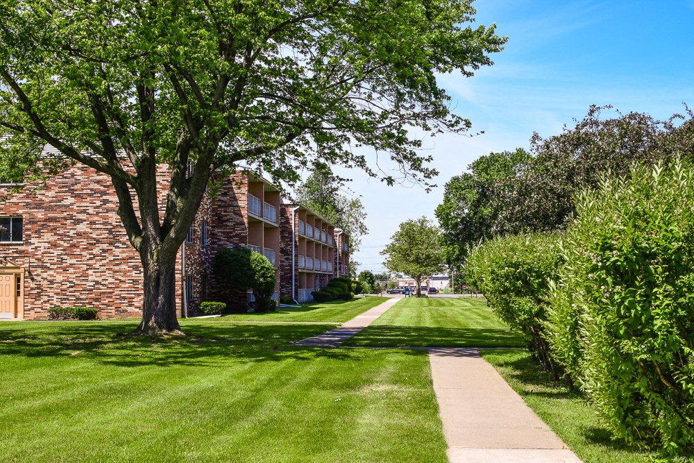 a green lawn in front of a brick apartment building