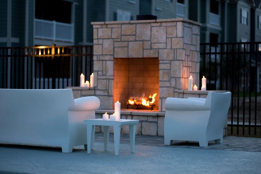 a fireplace on a patio with two white chairs and a coffee table at Plantation Crossing, Louisiana