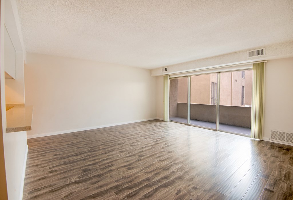 an empty living room with wood flooring and sliding glass doors