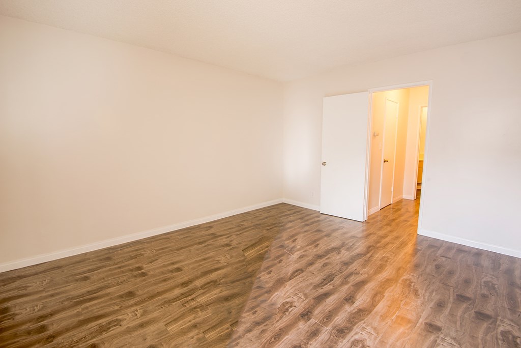 an empty room with wood flooring and white walls