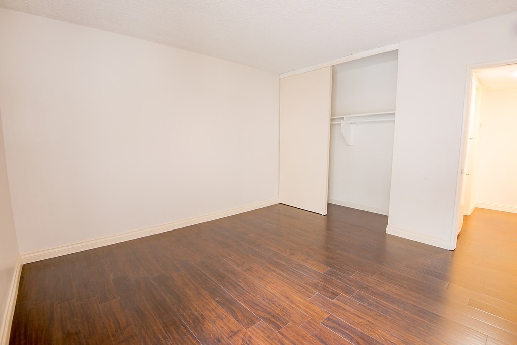 an empty room with wood flooring and a closet