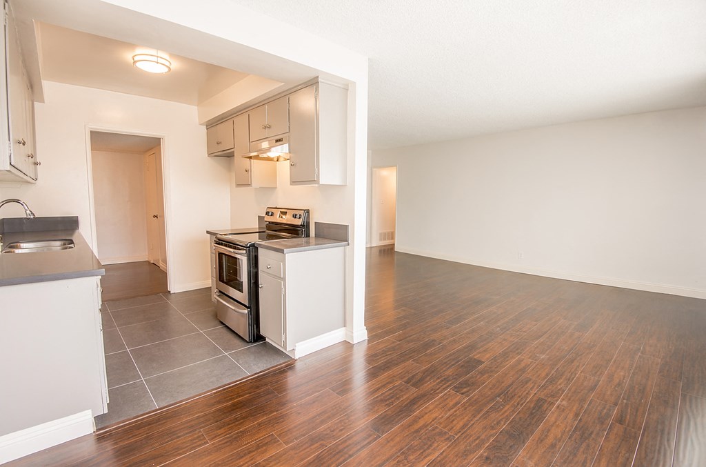 an empty kitchen and living room with a hard wood floor