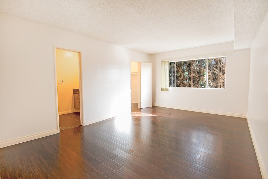 an empty living room with wood floors and a window