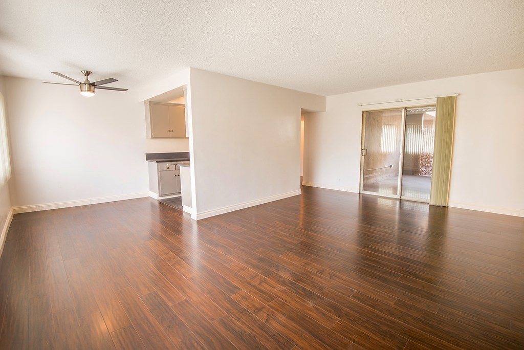 an empty living room with wood flooring and a ceiling fan