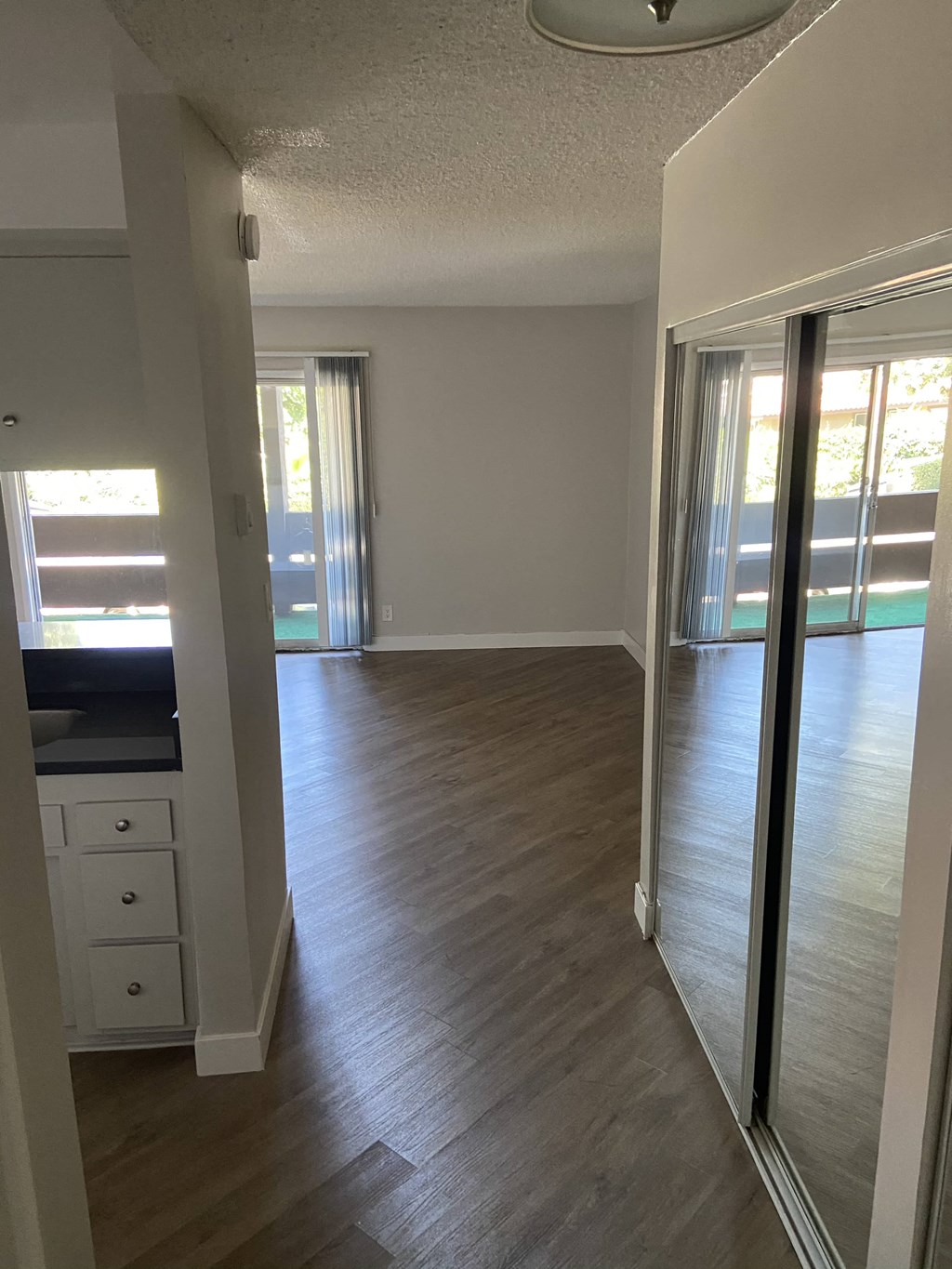 an empty living room with wood floors and a mirror