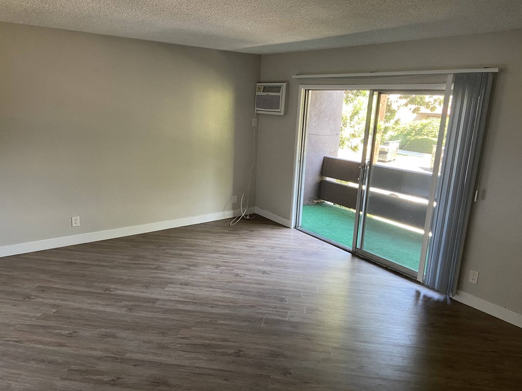 an empty living room with a sliding glass door to a patio
