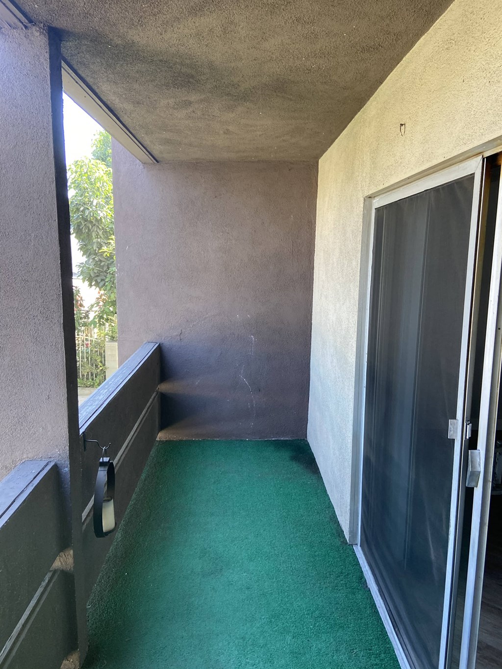 an empty room with a green carpet and a sliding glass door