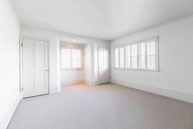 an empty living room with a white door and window