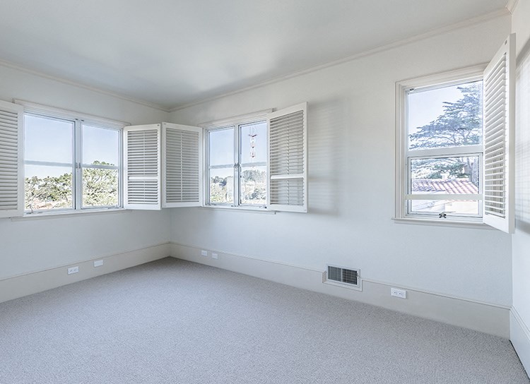 an empty room with white walls and windows