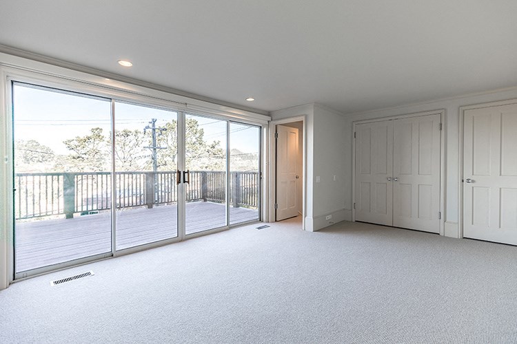 an empty living room with large windows and a balcony