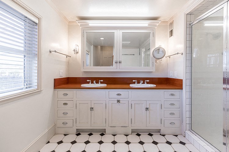 a bathroom with two sinks and a mirror and a shower