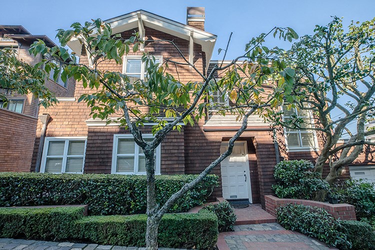 a brick house with a white door and a tree in front of it