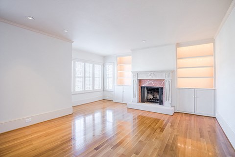 an empty living room with a fireplace and wooden floors