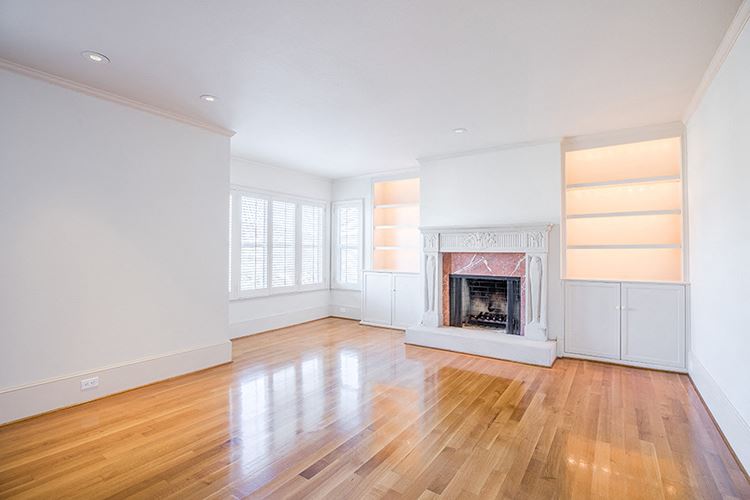 an empty living room with a fireplace and wooden floors