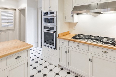 a kitchen with white cabinets and a black and white tiled floor