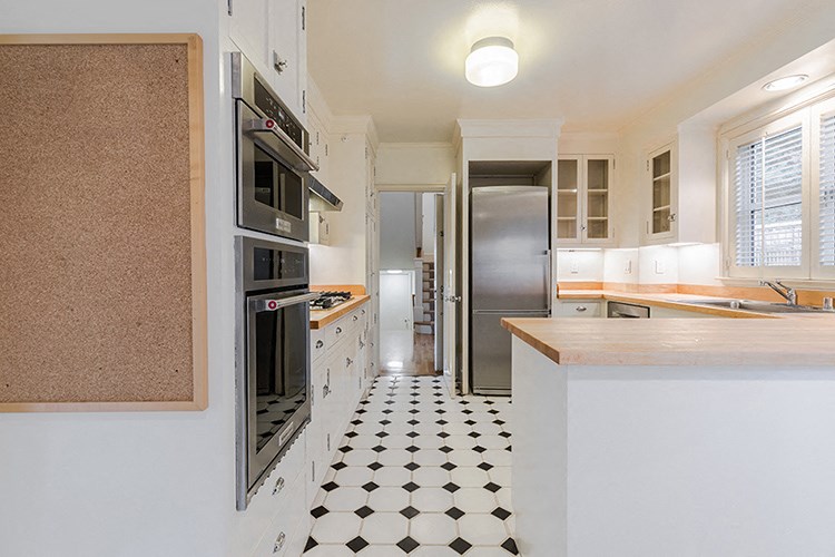 a kitchen with a black and white tiled floor and stainless steel appliances