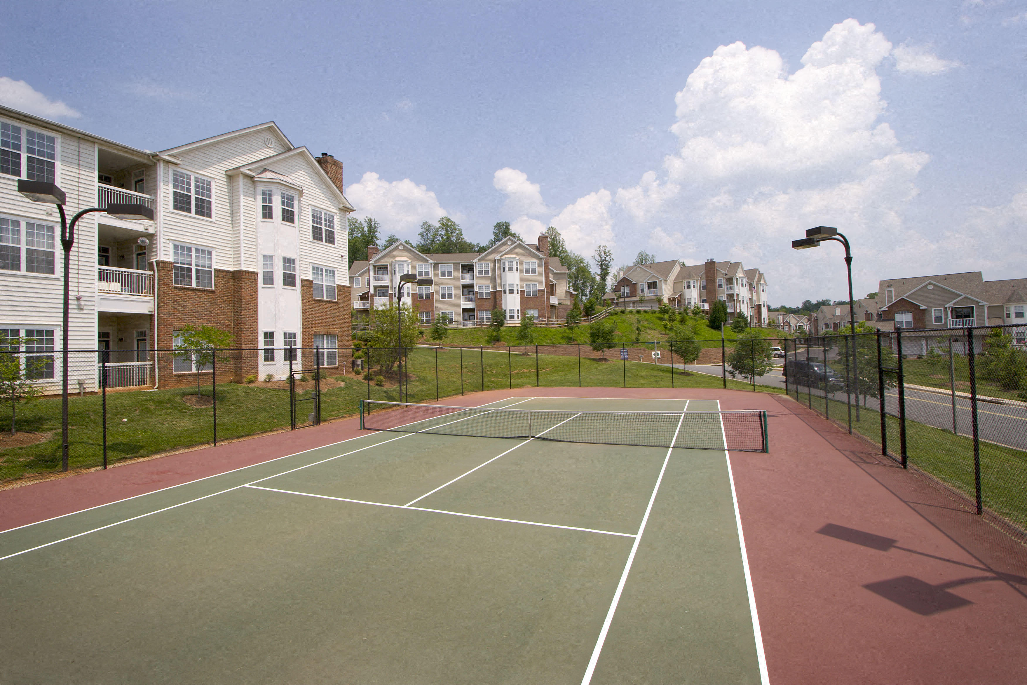 a tennis court with apartments in the background