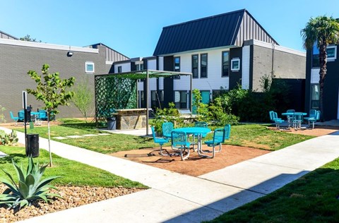A sunny day at a modern building with a green lawn and blue chairs.