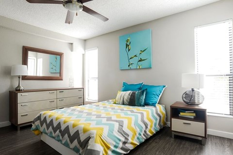 A bedroom with a bed, dresser, and ceiling fan.