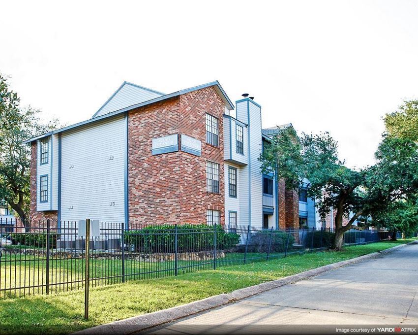 a brick and white building with a yard and a fence