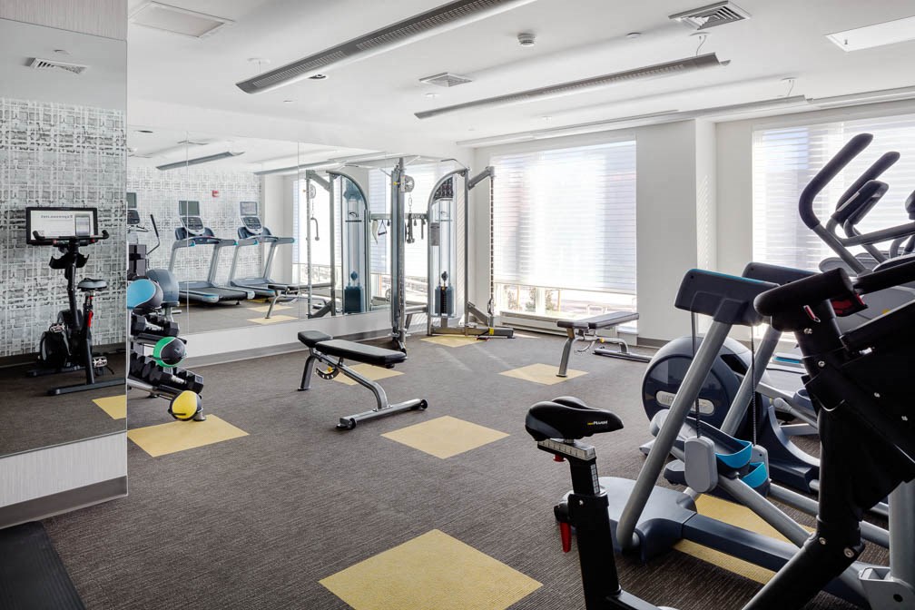 a gym with cardio equipment and windows in a building
