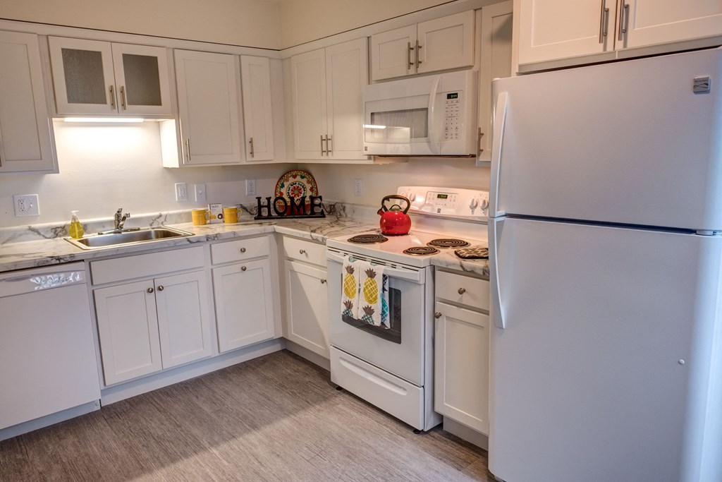 a kitchen with white cabinets and appliances and a white refrigerator