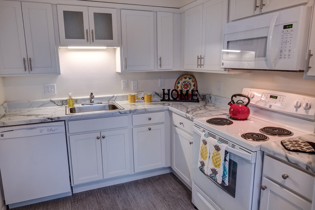 a kitchen with white cabinets and a stove and a sink