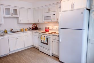 a kitchen with white cabinets and a white refrigerator