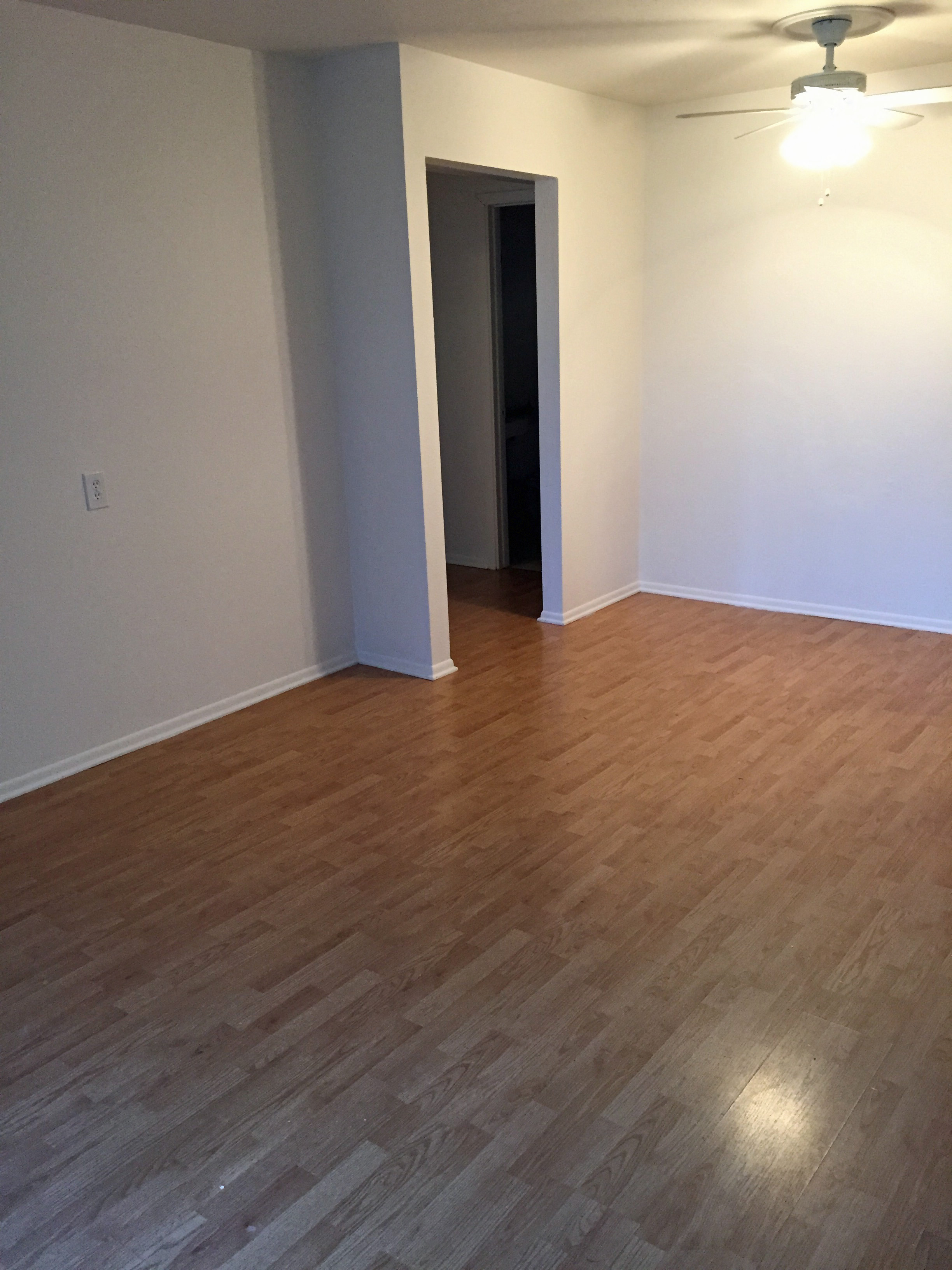 an empty living room with wood flooring and a ceiling fan