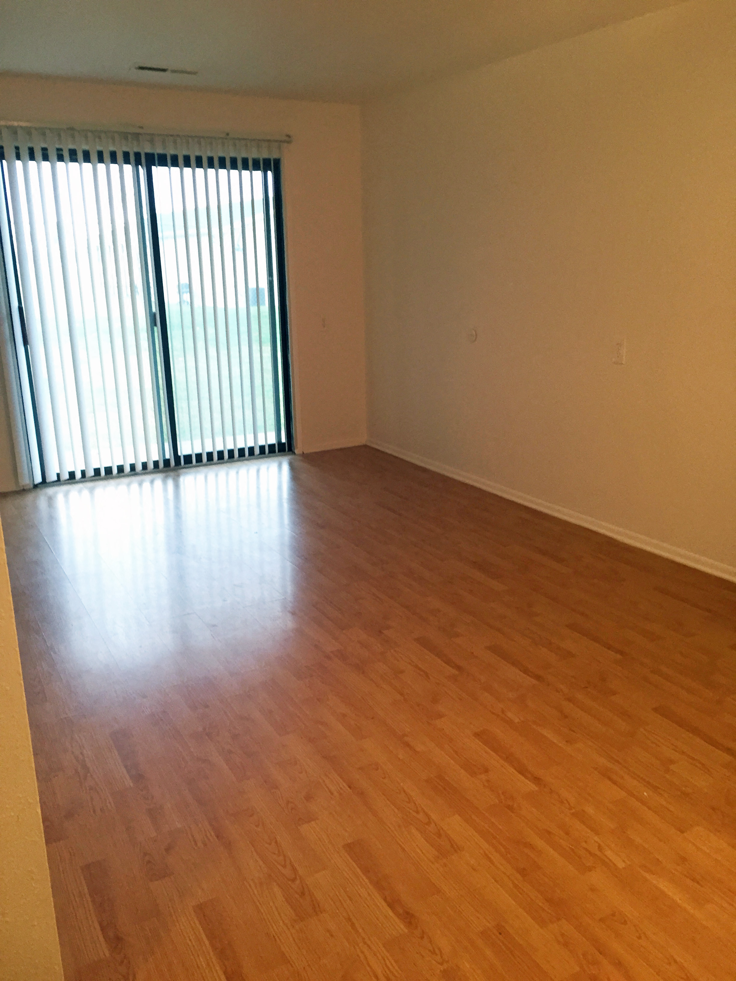 an empty living room with wood floors and a window