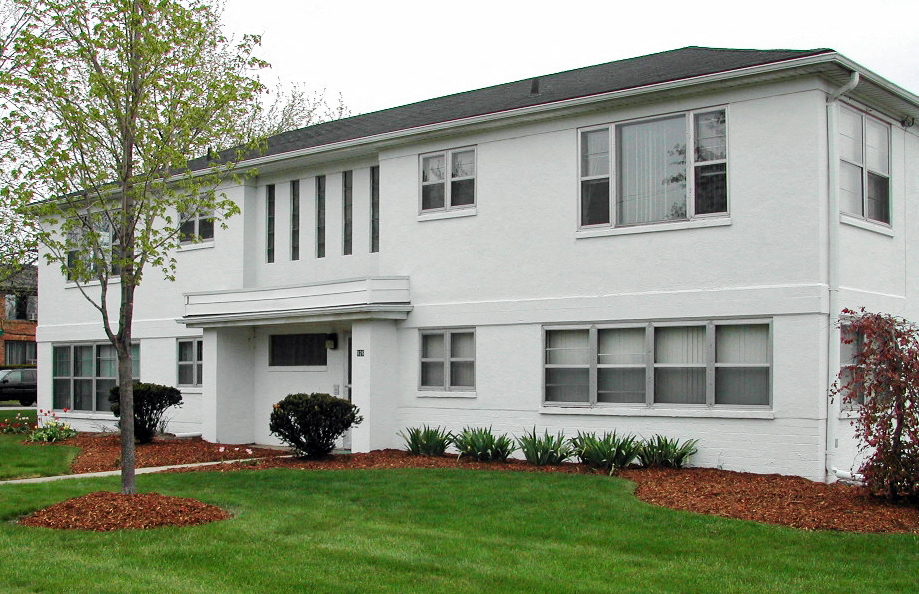 a white house with a lawn and a tree