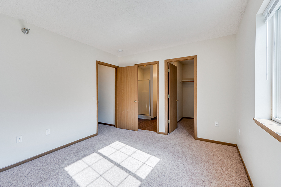 bedroom with open doors leading to a closet, a bathroom, and a hallway