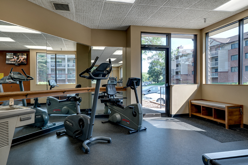 Fitness room with various equipment and a large mirror wall