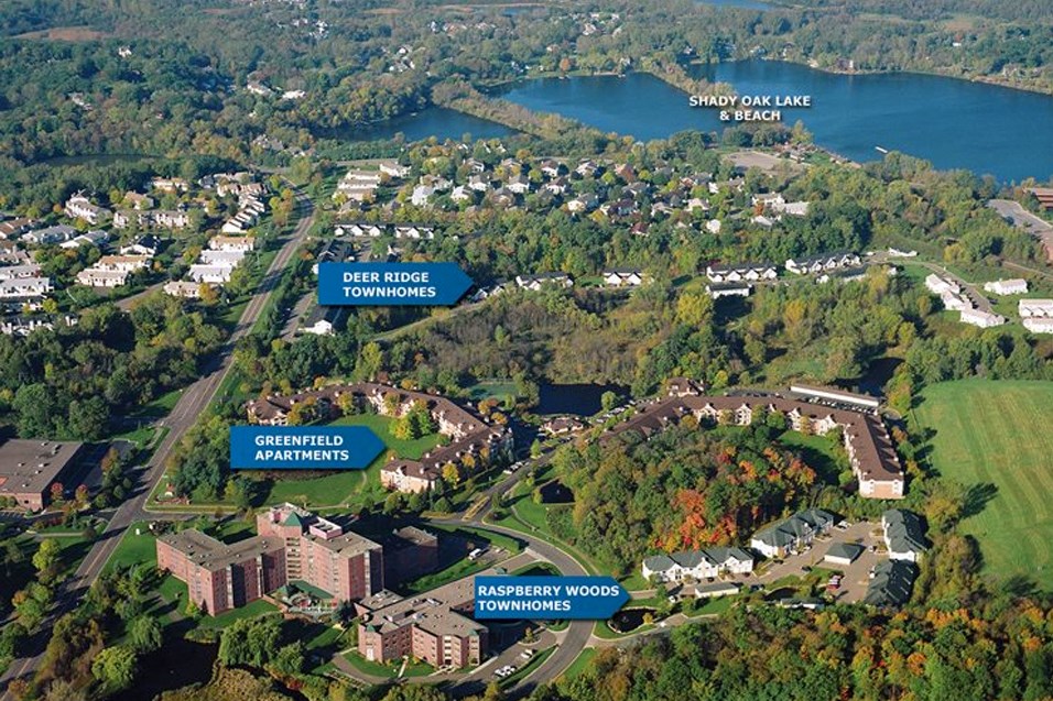 an aerial view of the campus with buildings and trees and a lake