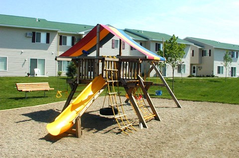 a playground with a swing set and slide in front of a house