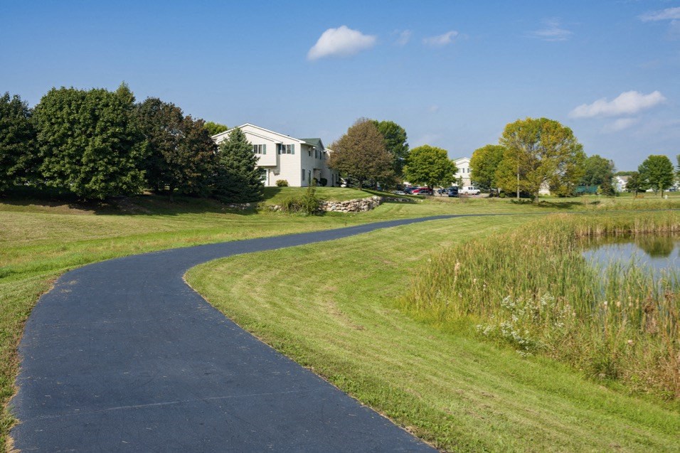 a winding path next to a pond and a house